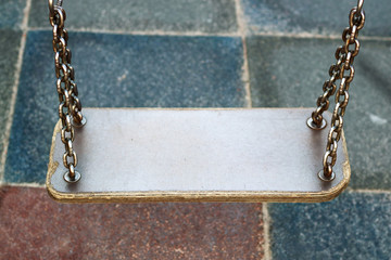 The swing is empty on the playground for children.