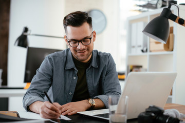 Young handsome man working in office. Bussinesman working on lap top in office.