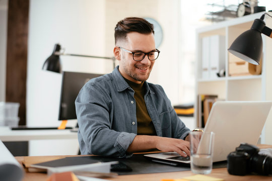 Young handsome man working in office. Bussinesman working on lap top in office.