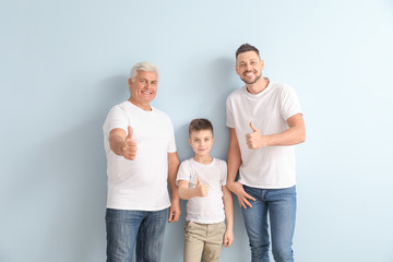 Man with his father and son showing thumb-up gesture on color background