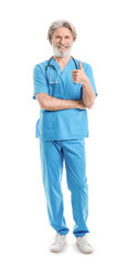 Portrait of senior male doctor showing thumb-up gesture on white background