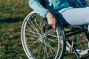 Close up of a young woman in a wheelchair while walking in a park on a sunny day. Recovery and...