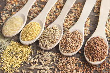 Composition of wooden spoons on which grains and cereals are located. Wheat, rice, buckwheat, millet, oats.
