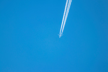 A white plane flies through the blue sky.