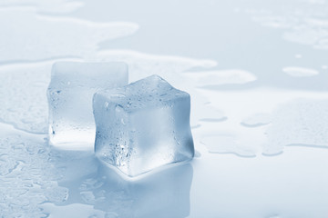 several melted ice cubes with drops on a light background with blue tinting
