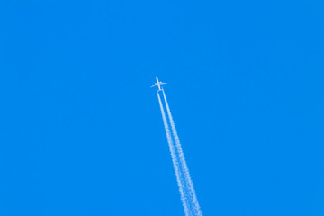 A white plane flies through the blue sky.