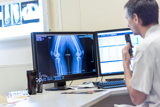 M&eacute;decin radiologue commente une radiographie sur &eacute;cran au dictaphone