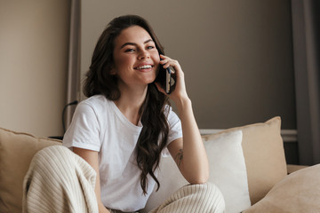 Beautiful young brunette woman relaxing on a couch at home