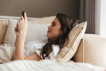 Beautiful young brunette woman relaxing on a couch at home