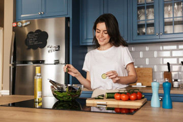 Beautiful young brunette woman cooking salad