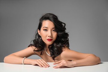 Naklejka premium Young Asian woman with beautiful hair on grey background