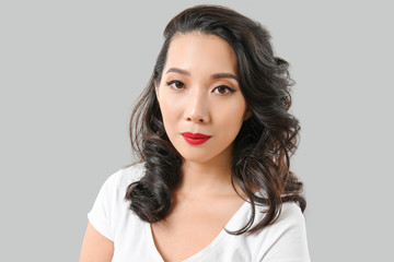 Fototapeta premium Young Asian woman with beautiful hair on grey background