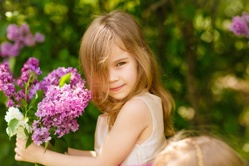 little girl in near a lilac flowers  with bouquet