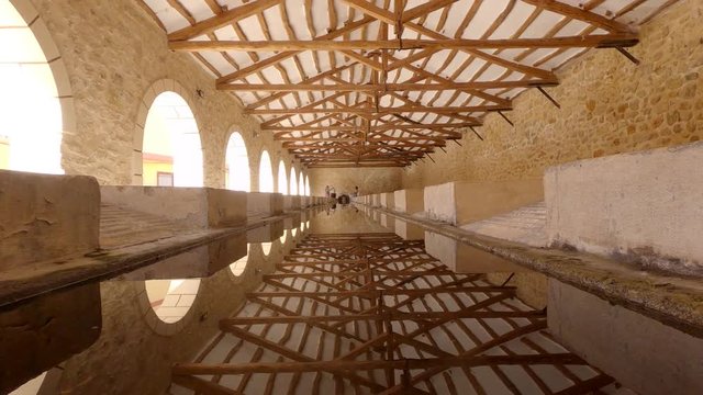 Lavadero simetrico y antiguo con vigas de madera y piedra natural