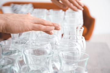 Young man playing music on glasses with water at home, closeup