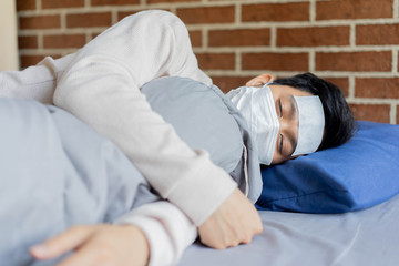 close up asian man sleeping on bed in bedroom after feeling fever in bedroom (quarantine area) for coronavirus preventive concept