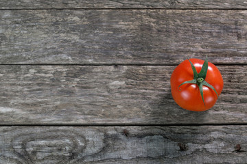 Eine Rote Tomate / Rispentomate auf rustikalem alten verwitterten Holz