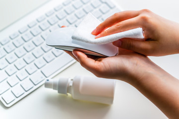 Cleaning the surface of the computer mouse. Coronavirus prevention, hygiene to stop spreading coronavirus.
