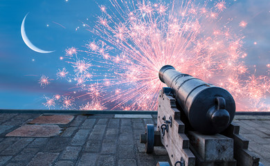 Ramadan Concept - Ramadan kareem cannon with crescent and fireworks - Night sky with moon in the clouds at sunset