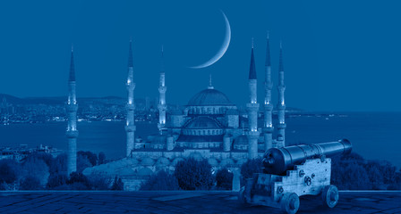 Ramadan Concept - Sultanahmet mosque and Bosphorus with crescent moon and cannon at twilight blue hour - Istanbul, Turkey