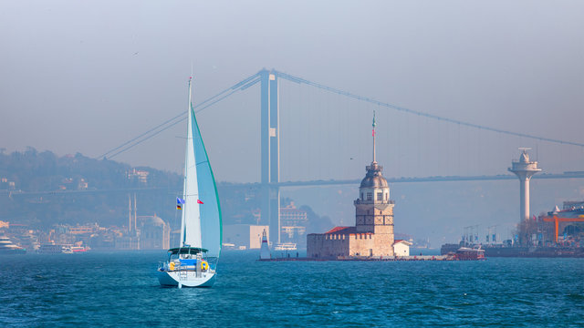 Sailing luxury yact in the bosphorus - Istanbul Maiden Tower (kiz kulesi) in the background Ortakoy Mosque and bosphorus bridge - Istanbul, Turkey