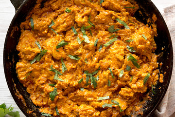 Homemade Chicken Tikka Masala in a cast iron pan on a white wooden surface, top view. Flat lay, overhead, from above. Close-up.