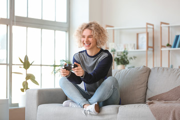 Beautiful young woman playing video games at home