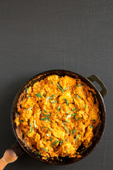Homemade Chicken Tikka Masala in a cast iron pan on a black background, top view. Flat lay, overhead, from above. Space for text.