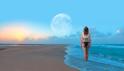 Beautiful Woman Walking On the Beach  with full moon at sunset 