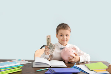 Little accountant at table against grey background