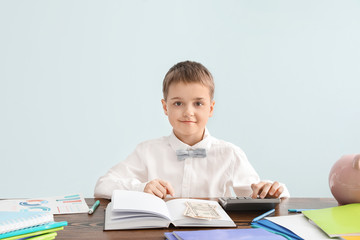 Little accountant at table against grey background