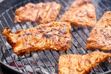 cooking, culinary and food concept - close up of barbecue meat roasting on brazier grill outdoors
