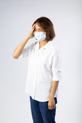 Portrait of Asian Sick woman having headache migraine with protective mask on white background. Mask protection against virus. Covid-19, coronavirus pandemic