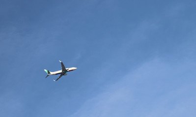 Closeup of an airplane flying with blue sky background.