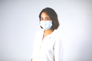 Studio portrait of Asian woman wearing face medical surgical mask, looking at camera, isolated on white background. Mask protection against virus. Covid-19, coronavirus pandemic