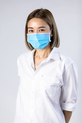 Studio portrait of Asian woman wearing face medical surgical mask, looking at camera, isolated on white background. Mask protection against virus. Covid-19, coronavirus pandemic