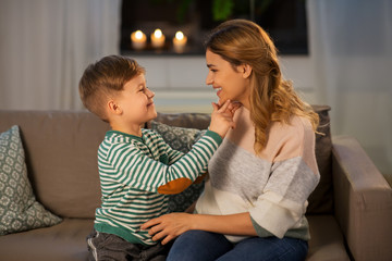 family, love and people concept - happy smiling mother talking to her little son in evening