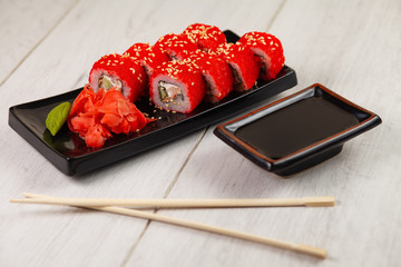 Hand holds chinese chopsticks with sushi on food background