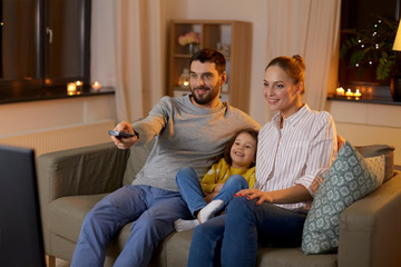 family, leisure and people concept - happy smiling father with remote control, mother and little...