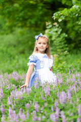 Fototapeta na wymiar Portrait of a little cute girl dressed as Alice. Stylized photo shoot in nature.