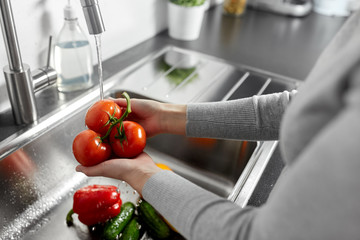 hygiene, health care and safety concept - close up of woman's hands washing vegetables in kitchen...