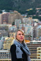 Portrait of young woman with white hairs and black jacket in front of the Monaco cityscape background during cloudy day