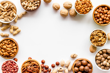 Nuts set in bowls on white background top-down frame copy space