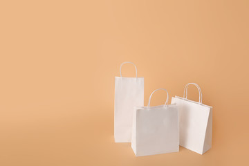 Paper shopping bags on color background