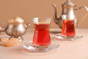 Tasty Turkish tea with sweets on color background
