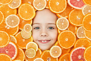 The face of a child is surrounded by oranges. The Importance and Need of Vitamin C for the Baby