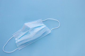  used medicine mask with rubber ear straps on blue background. Protect from virus and bacteria concept