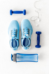 Sport equipment. Sneakers, dumbbells and water on white table top view flat-lay