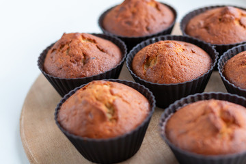 Homemade muffins on a wooden board near the window