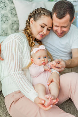 Beautiful young parents are holding their little newborn daughter in their arms. Blue-eyed little girl of 2 months. Baby